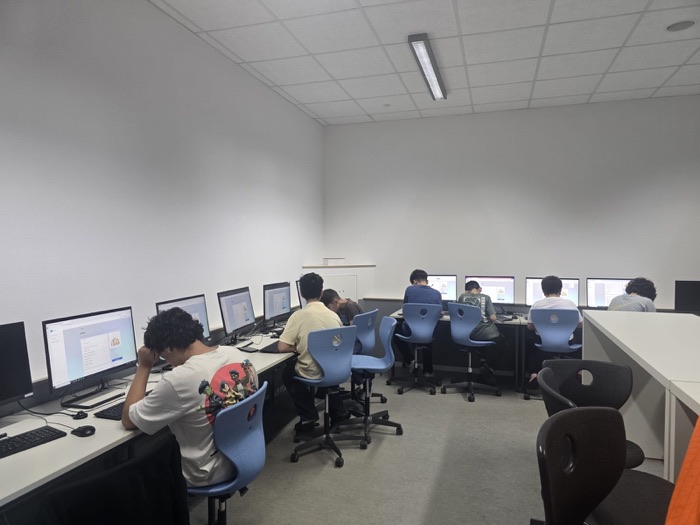 Students seated along a row of monitors, each working through the UP-RES portal.