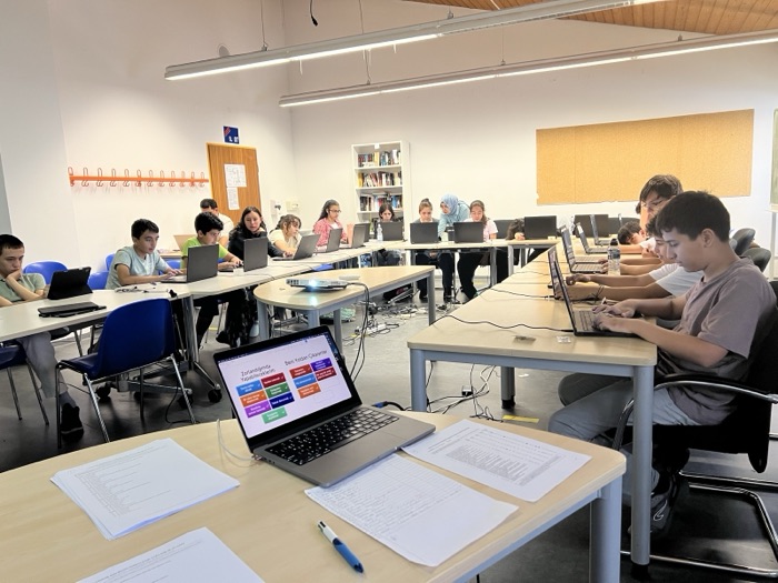 Students working at laptops during a piloting workshop, with a resilience exercise open on the screen in the foreground.